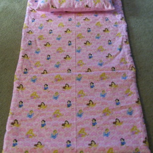 May include: A pink sleeping mat with a princess pattern and a matching pillow. The mat has a carrying handle.