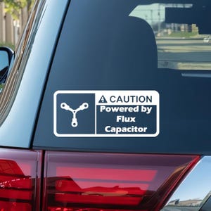 May include: White vinyl sticker with a warning sign that reads "CAUTION Powered by Flux Capacitor". The sign features a stylized image of a flux capacitor.
