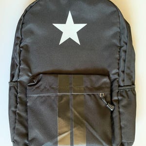 May include: Black backpack with a white star on the front and a black stripe on the front pocket.