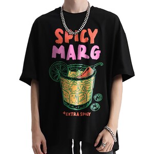 May include: Black t-shirt with a colorful graphic of a spicy margarita cocktail. The text "SPICY MARG" is above the cocktail illustration, and "EXTRA SPICY" is below. The design includes a lime slice and a chili pepper.