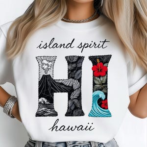 May include: White t-shirt with the words "island spirit" and "hawaii" in black script. The large "HI" in the center features volcano, leaf, and wave designs. The "H" has a volcano design, the "I" has a red hibiscus flower and blue wave design.