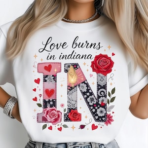 May include: White t-shirt with the phrase "Love burns in Indiana" and a decorative "IN" design. The design includes hearts, roses, and floral patterns in pink, red, and black.