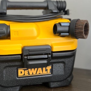 Może przedstawiać: Żółto-czarny odkurzacz DeWalt do pracy na mokro i na sucho z czarnym wężem i szczotką.