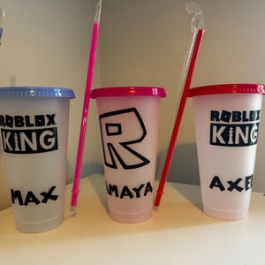 Reusable plastic cups with lids and straws. The cups are decorated with the words "Roblox King" and names.