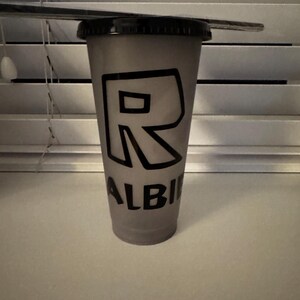 Puede incluir: Un vaso reutilizable gris con una letra "R" negra y la palabra "ALBI" impresa en &eacute;l.
