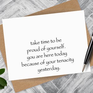 May include: A white card with the text "take time to be proud of yourself. you are here today because of your tenacity yesterday."