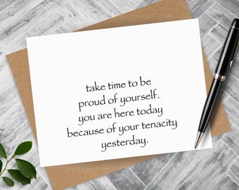 May include: A white card with the text "take time to be proud of yourself. you are here today because of your tenacity yesterday."