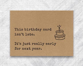 May include: A brown birthday card with black text and a small cake illustration. The text reads: "This birthday card isn't late. It's just really early for next year."