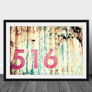 May include: A close-up of a rusty metal surface with the number 516 painted in pink.