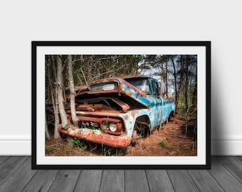 Könnte beinhalten: Ein blauer und rostiger Pickup-Truck ist teilweise in einem Wald versunken. Dem Truck fehlt die Motorhaube und ein Baum wächst durch die Fahrertür. Der Truck ist von Bäumen und Gestrüpp umgeben.