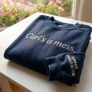 Può includere: Felpa blu navy con la scritta ricamata "Carl's a mess." sul davanti. Il polsino della manica mostra la scritta ricamata "SUMMER SHOULD BE FUN."