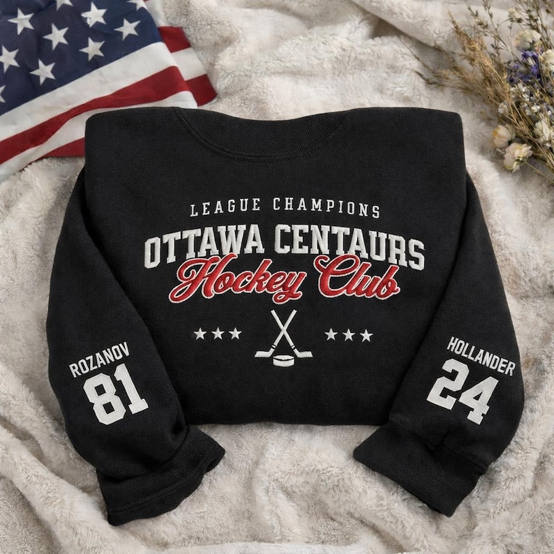 May include: Black crewneck sweatshirt with the text "LEAGUE CHAMPIONS OTTAWA CENTAURS Hockey Club" in white and red. The sleeves display the names and numbers "ROZANOV 81" and "HOLLANDER 24". A hockey stick and puck graphic is also present.