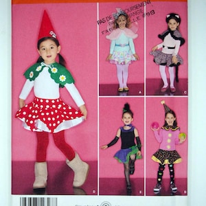 May include: Simplicity sewing pattern 2327 for children's costumes in size A 3,4,5,6,7,8. The envelope features illustrations of five different outfits including a gnome, fairy, cat, witch, and clown, showcasing various skirts, capes, and hats.