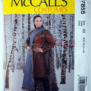 May include: A McCall's sewing pattern for a costume, featuring a woman wearing a brown leather jacket with a fur-trimmed cape. The pattern is for sizes 6-8-10-12-14.