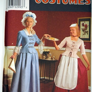 May include: Simplicity Costumes pattern showing two women in historical dress. One wears a light blue dress and bonnet, holding a cloth. The other wears a pink bodice, white apron, and red skirt, holding a plate. The pattern is for costumes.