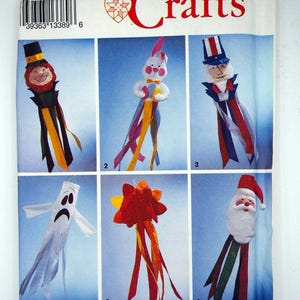 May include: A Simplicity Crafts pattern featuring six whimsical fabric craft projects. The projects include a leprechaun, a bunny, Uncle Sam, a ghost, a flower, and Santa Claus. The pattern is designed by Wendy Everett.