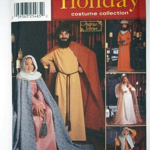 Può includere: Una busta per cartamodello Simplicity Holiday costume collection, numero 7029, con illustrazioni di vari costumi storici e religiosi, tra cui tuniche, mantelli e un costume da angelo con ali, il tutto su uno sfondo rosso e bianco.