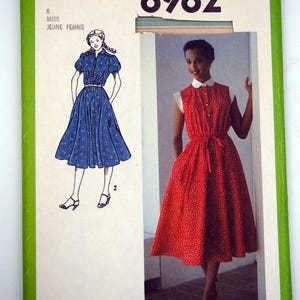 Peut inclure: Patron de couture Simplicity 8982 vintage. L'emballage vert et blanc présente des illustrations de deux robes : une robe bleue à fleurs et une robe rouge à pois. Le paquet comprend également le texte "PATTERN/PATRON" et "MISS JEUNE FEMME".
