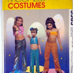 Peut inclure: Une pochette de patron de couture McCall's Costumes montrant trois enfants portant des tenues deux pièces. La tenue de gauche comprend un haut rose et un pantalon argenté métallisé. Le centre est un haut et un pantalon bleus à sequins.