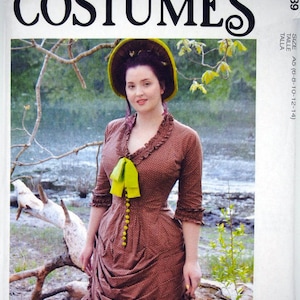 May include: A brown and white polka dot dress with a green bow and yellow buttons. The dress has a ruffled skirt and a fitted bodice. The model is wearing a green hat and has dark hair. The image is from a McCall's Costumes pattern.