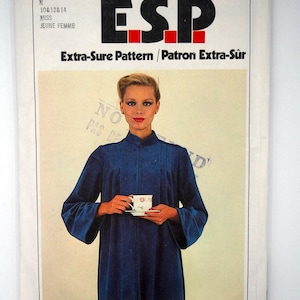 May include: A vintage Simplicity sewing pattern envelope featuring a woman in a blue dress holding a teacup. The envelope has the text "ESP" in large black letters with red squares, and the text "Extra-Sure Pattern / Patron Extra-Sûr".