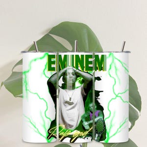 May include: Three white stainless steel tumblers with green lightning bolts and the words "EMINEM" and "Rap God" in black and gold lettering. The tumblers feature a photo of Eminem with his hands on his head.
