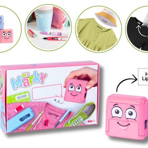 May include: Pink My Marky self-inking stamp with a smiling face. The stamp is used to create personalized labels for clothing, shoes, and other items. The image shows a close-up of the stamp and a sample label with the name "Hania Lipińska" and a ladybug.