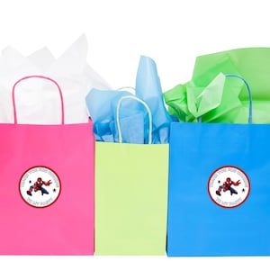 Puede incluir: Tres bolsas de regalo con papel de seda en su interior. Las bolsas son rosa, verde y azul. Cada bolsa tiene una pegatina redonda con un personaje de superh&eacute;roe de dibujos animados y el texto "Gracias por venir a mi fiesta".