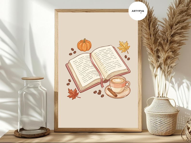 May include: A framed wall art print featuring an open book with a pink bookmark, a pumpkin, a coffee cup on a saucer with a cinnamon stick, scattered coffee beans, and two autumn leaves on a light beige background with the text ARTYPINK.