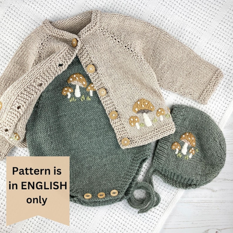May include: A knitted baby outfit set in beige and green, featuring a cardigan, romper, and hat. The set is adorned with mushroom embroidery and wooden buttons. The text "Pattern is in ENGLISH only" is visible.