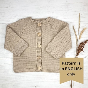 May include: A beige long-sleeve knit cardigan featuring a round neckline and five light brown wooden buttons down the center front. A tan banner overlay on the right side displays the text: Pattern is in ENGLISH only.