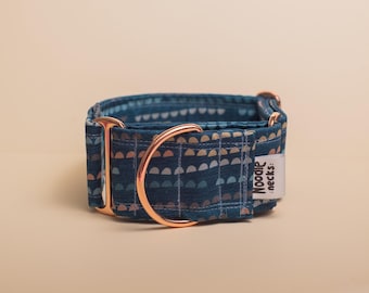 Puede incluir: Un collar para perro de tela azul verdoso oscuro con un patrón repetitivo de pequeños semicírculos claros. El collar incluye herrajes de metal en oro rosa, incluyendo una anilla en D y un ajustador, y una etiqueta de tela blanca Noodle :necks:.