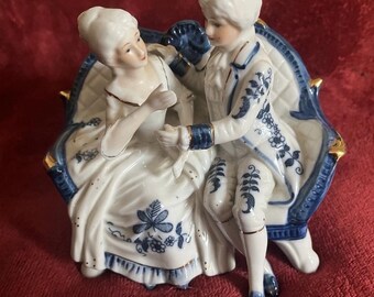 Ceramic vintage ornament of a loving couple on ornate sofa