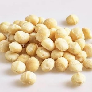 Può includere: Primo piano di un mucchio di noci di macadamia. Le noci sono di colore marrone chiaro e hanno una superficie liscia e lucida.