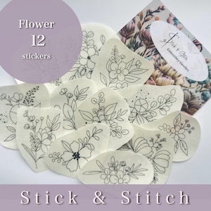 Peut inclure: Un ensemble de 12 autocollants de transfert de broderie de fleurs. Les autocollants sont blancs avec des contours noirs de différents motifs de fleurs. Les autocollants sont disposés en cercle sur un fond blanc. Le texte "Flower 12 stickers" est imprimé sur un cercle violet dans le coin supérieur gauche de l'image. Le texte "Stick & Stitch" est imprimé en noir sur un fond violet en bas de l'image.