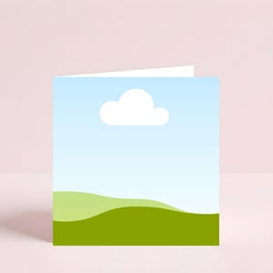 May include: A folded greeting card featuring a landscape design. The front of the card displays a blue sky with a white cloud and green rolling hills. The card is set against a pink background.