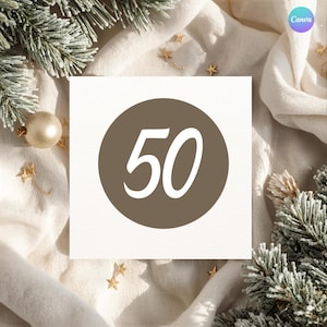 May include: A square card with the number 50 in white script inside a brown circle. The card is on a white cloth with gold star-shaped decorations and a gold ornament. Green and white frosted pine branches are in the background.