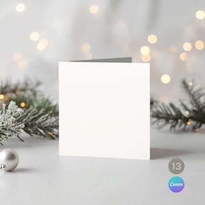 Peut inclure: Une carte de vœux carrée vierge avec une surface texturée, sur un fond festif. La carte est blanche, avec une tranche grise. Une boule argentée et des branches de conifères avec des lumières sont en arrière-plan. Le logo Canva est visible.