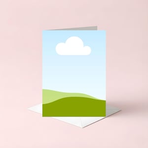 May include: Greeting card featuring a minimalist landscape design. The card displays a blue sky with a white cloud, and green rolling hills. The card is set on a white envelope against a pink background.