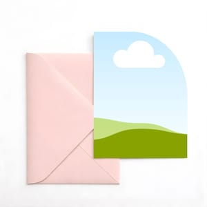 May include: A light pink envelope next to a card with a blue sky, white cloud, and green hills design. The card has a rounded top edge. The envelope is folded and sealed.