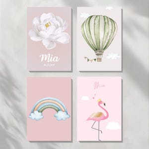 May include: Four watercolor art prints. One features a white peony with the name "Mia" and date. Another shows a green and white striped hot air balloon. A third print has a rainbow. The last print is a pink flamingo.