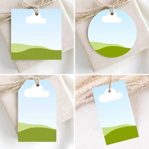 May include: Four gift tags with a landscape design. Each tag features a blue sky with a white cloud and green rolling hills. The tags are square, round, rectangular, and a tag shape, all with a hole for string.