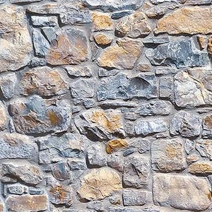May include: A close-up of a stone wall with a mix of grey, brown, and tan stones. The stones are arranged in a random pattern, creating a rustic and textured look.