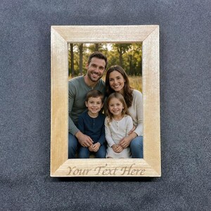 May include: A rectangular wooden picture frame with a family portrait. The frame has a light wood finish and the text "Your Text Here" is engraved at the bottom. The family includes two adults and two children.