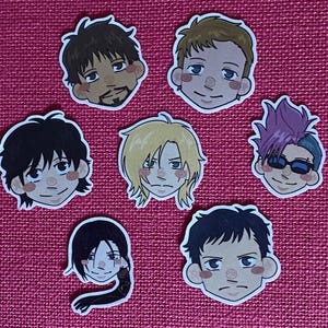May include: Seven anime-style character face stickers. The stickers depict different hairstyles and expressions, with a variety of skin tones and hair colours, including black, blonde, and purple. The stickers are set against a pink background.