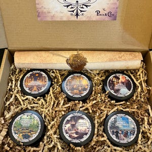 May include: A gift box filled with six black-lidded tins, each with a different illustration and scent name. The box includes a scroll and a wax seal. The text on the box reads "collection was unveiled, each scent a whispered secret from the magical world."