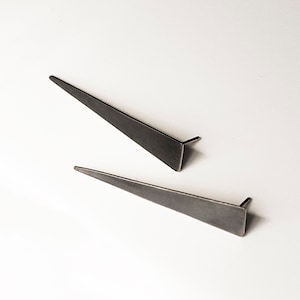 May include: A pair of silver triangle shaped earrings. The earrings are simple and modern in design.