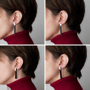 Puede incluir: Primer plano de una persona que lleva un jersey de cuello alto rojo y pendientes geom&eacute;tricos en blanco y negro. Los pendientes son largos y cuelgan de los l&oacute;bulos de las orejas.