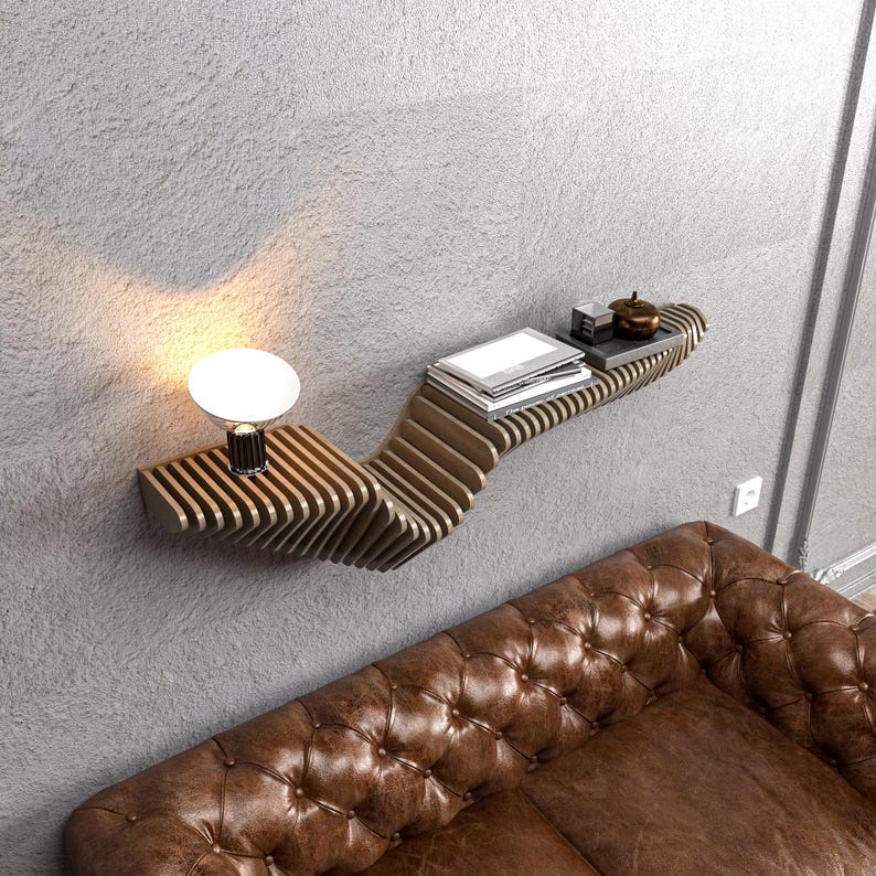 Pode incluir: Uma prateleira de parede de madeira com um design ondulado &uacute;nico. A prateleira est&aacute; montada em uma parede cinza e tem uma pequena l&acirc;mpada e livros.