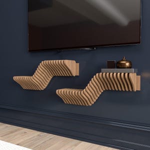 Pu&ograve; includere: Due mensole a muro in legno con un design ondulato. Le mensole sono montate su una parete blu scuro. La mensola superiore &egrave; vuota e la mensola inferiore ha un piccolo oggetto decorativo sopra.